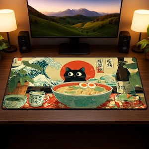 May include: A rectangular desk mat featuring a Japanese-inspired design. The mat showcases a black cat peering over a bowl of ramen, with a red sun and a wave pattern in the background. Additional elements include a cup, a small bowl, and a bottle.