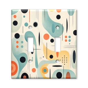 May include: A double light switch wall plate featuring a cream background with an abstract pattern of teal, orange, and black shapes, including circles, dots, and thin vertical and horizontal lines, with two rectangular cutouts for switches.