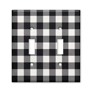 May include: A rectangular double light switch wall plate featuring a black, white, and gray buffalo check plaid pattern. The cover includes two vertical rectangular cutouts for toggle switches and four circular holes for mounting screws.
