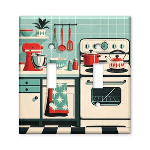 May include: A double light switch cover featuring a kitchen illustration with a red stand mixer, a stove with a kettle, hanging utensils, and a teal tiled backsplash. The design includes a checkered floor and a patterned towel on the oven door.