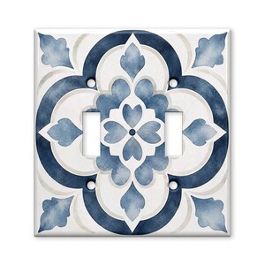 May include: A double light switch wall plate featuring a symmetrical watercolor pattern in shades of navy blue, light blue, and white. The design consists of interlocking curved shapes and floral-inspired motifs with four screw holes.