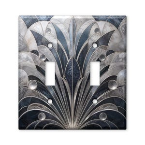 May include: A double light switch wall plate featuring a symmetrical fan-like pattern in shades of navy blue, slate gray, and white. The design consists of curved, overlapping segments with a marble-like texture and circular accents.