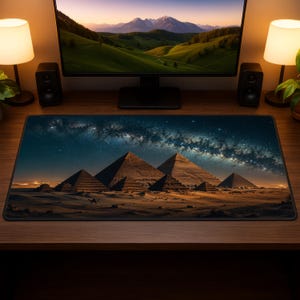 May include: A rectangular desk mat featuring a high-resolution print of the Giza pyramids at night under a starry Milky Way galaxy sky. The scene depicts the desert landscape with silhouettes of pyramids and camels against a dark blue night sky.