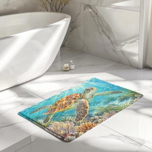May include: A rectangular bath mat featuring a vibrant underwater scene with a sea turtle swimming above a colorful coral reef. The design displays shades of turquoise, blue, orange, and brown, capturing the turtle in clear water.