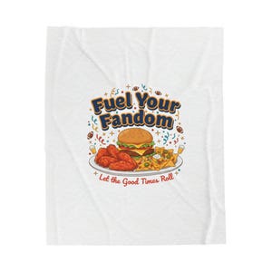 May include: White blanket with a graphic of a burger, chicken wings, and nachos on a plate. The text "Fuel Your Fandom" is above the food, with "Let the Good Times Roll" below. Footballs and confetti are scattered around the image.