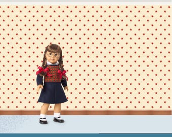 Può includere: Una bambola con un vestito blu navy, un maglione rosso e verde e scarpe nere. La bambola ha i capelli castani a trecce con fiocchi rossi e indossa occhiali. Lo sfondo è una parete color crema con motivi a stella rossa.
