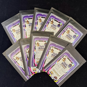 May include: A collection of sealed, dark gray pouches, each containing a card game. The pouches feature a purple and white design with the text "Dark Blokes" and cartoon illustrations. The cards inside are not visible.
