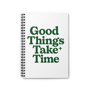 Puede incluir: Cuaderno de espiral blanco con el texto "Good Things Take Time" en letras verde oscuro. El cuaderno tiene un diseño limpio y minimalista, perfecto para tomar notas o anotar ideas.