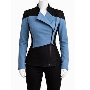 May include: A two-tone jacket in black and light blue, displayed on a mannequin. The jacket features a high collar, an asymmetrical zip, and a fitted silhouette. The sleeves are long, and the design incorporates geometric colour blocking.