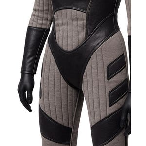 May include: A gray and black jumpsuit with a futuristic design. The suit features vertical ribbed panels in gray, contrasted by black leather-like accents on the shoulders, chest, and legs. Black gloves complete the look.