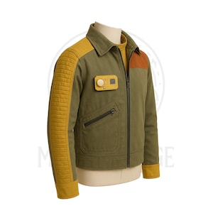 Könnte beinhalten: Olivgrüne Jacke mit gesteppten Ärmeln und Akzenten in Senfgelb. Die Jacke hat einen braunen Schulteraufnäher, einen kleinen gelben quadratischen Aufnäher und einen schwarzen Reißverschluss. Die Jacke wird auf einer Schaufensterpuppe präsentiert.