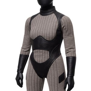 Premium dual-fabric construction: ribbed stretch base + faux leather armor overlay

Tailored body-contour seams for a sculpted fit

High-neck collar and long integrated sleeves

Reinforced stitched panels on torso, arms, and thighs

Hidden rear zip for seamless closure