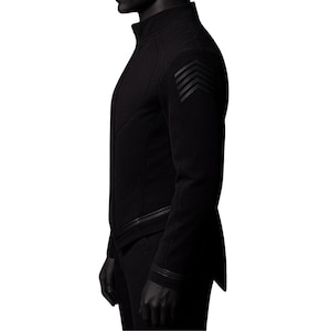 May include: Black jacket with a high collar and angled seams. The jacket features a series of three angled stripes on the upper arm and a zipper detail. The garment is a solid black color.