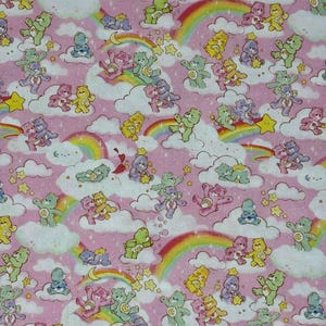 Peut inclure: Un tissu rose à motif répétitif représentant des Bisounours dans diverses positions, assis, debout ou jouant sur des nuages blancs. Le design comprend des arcs-en-ciel colorés, des étoiles jaunes et de petits croissants de lune dispersés.