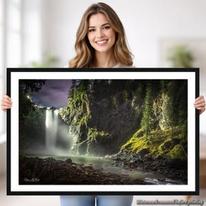 Pode incluir: Uma fotografia de paisagem emoldurada apresentando uma cascata que desce por uma falésia rochosa coberta de musgo verde e árvores perenes. A cena inclui um leito de rio rochoso e escuro em primeiro plano e um céu com tons de roxo. O texto Vince Le Point é visível.