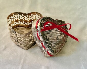 Silver tone heart shaped metal trinket box, with red ribbon.
