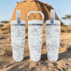 May include: Three white Stanley tumblers with a repeating black line art pattern of aardvarks, termite mounds, and small insects. Each tumbler features a white lid with a sturdy handle and the Stanley logo printed on the centre vessel.