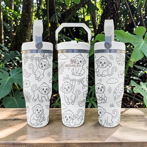 May include: Three white Stanley tumblers with a repeating black line art pattern of monkeys, bananas, tropical leaves, and flowers. Each tumbler features a white lid with a sturdy carrying handle and a metallic rim detail near the top.