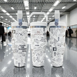 Puede incluir: Tres vasos t&eacute;rmicos blancos con tem&aacute;tica de viaje, con ilustraciones en blanco y negro de aviones, equipaje e iconos de viaje. El texto "READY FOR TAKEOFF" y "TIME FOR ANOTHER ADVENTURE!" son visibles. Cada vaso tiene un asa y una tapa blancas.