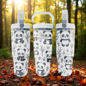 May include: Three white insulated tumblers featuring panda bear designs and the Stanley logo. Each tumbler has a white handle and a grey accent. The panda bears are black and grey, set against a white background with bamboo and floral patterns.