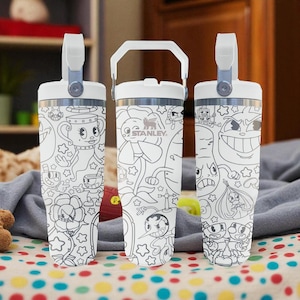 Puede incluir: Tres tazas de viaje Stanley blancas con diseños de personajes de dibujos animados en blanco y negro. Cada taza tiene un asa y una tapa blancas. Las tazas están sobre una superficie de lunares de colores.