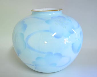 以下が含まれることがあります： 丸い水色の花瓶で、内側は白、縁は金色です。花瓶は青色の濃淡で花柄が施されています。デザインは、様式化された花と流れるようなラインが特徴です。