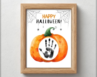 May include: A framed Halloween print with a watercolour pumpkin design. The pumpkin has a green stem and a black handprint in the centre. The words "HAPPY HALLOWEEN!" are above the pumpkin, with spiderwebs and spiders. The frame is made of light-coloured wood.