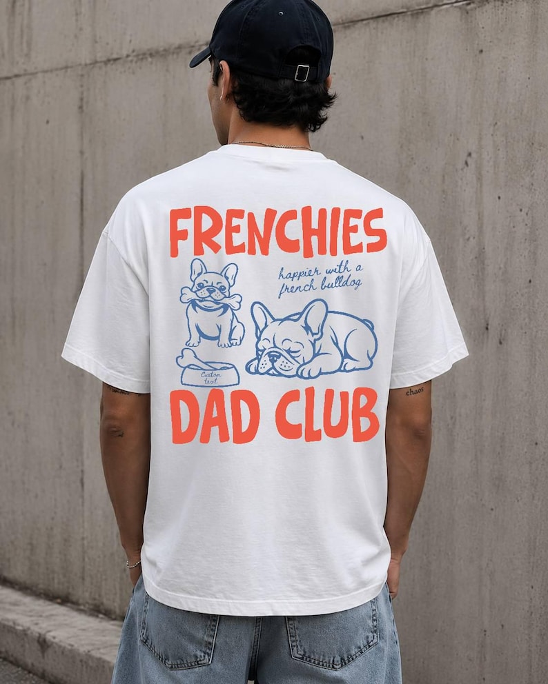 May include: White t-shirt with the words "FRENCHIES" and "DAD CLUB" in orange, and two blue French bulldog illustrations. The shirt also has the text "happier with a french bulldog".