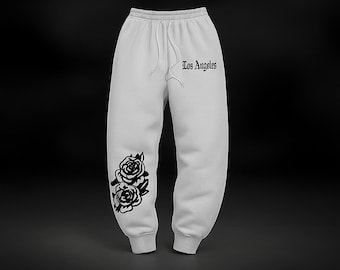 May include: Light gray sweatpants with a drawstring waist and the text "Los Angeles" in black script. The left leg features a black rose graphic. The pants are made of a soft material.