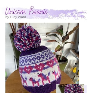 Peut inclure: Bonnet en tricot violet et blanc avec un pompon rose et blanc. Le bonnet a un motif d'unicornes roses sur fond blanc. Le bonnet est sur une surface en bois.