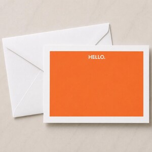May include: A rectangular greeting card with a solid orange background and the word HELLO. printed in white at the top center, accompanied by a plain white envelope positioned behind the card to show a complete stationery set.