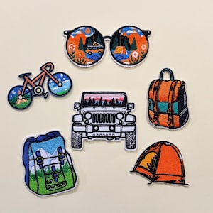 May include: A selection of embroidered camping-themed patches. Designs include sunglasses with a landscape scene, a bicycle, a backpack, a Jeep, a tent, and a backpack with the text "GET OUTSIDE".