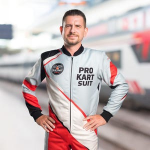 K&ouml;nnte beinhalten: Eine Person in einem grau-roten und schwarzen Pro Kart Anzug mit dem Wort "RACING" auf der linken Brust. Der Anzug hat einen Rei&szlig;verschluss und die Worte "PRO KART SUIT" auf der rechten Brust.