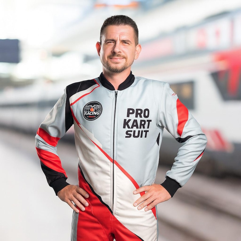 K&ouml;nnte beinhalten: Eine Person in einem grau-roten und schwarzen Pro Kart Anzug mit dem Wort "RACING" auf der linken Brust. Der Anzug hat einen Rei&szlig;verschluss und die Worte "PRO KART SUIT" auf der rechten Brust.