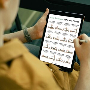 Może przedstawiać: Tablet z instrukcją ćwiczeń Pilates. Tytuł to "Back & Posture Reformer Pilates", z ilustracjami i opisami pozycji. Tablet jest czarny z białym obramowaniem. Osoba trzymająca go ma na sobie beżową koszulę.
