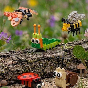 May include: A collection of four small plastic building block figures including a peach-colored butterfly, a yellow and black striped bee, a green caterpillar with orange antennae, and a red ladybug, plus a tan snail with a brown shell.