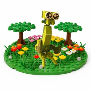 May include: A lime green robot figure made of interlocking blocks stands on a green base with colorful flowers and two green trees. The robot has large, round eyes and articulated limbs, resembling a whimsical creature.