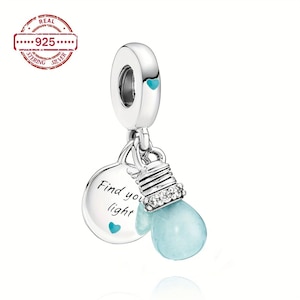 May include: A silver charm with a light blue teardrop-shaped bead, resembling a lightbulb, hangs from a silver loop. A silver disc with the words "Find your light" and a small blue heart is also attached. The charm is made of .925 sterling silver.