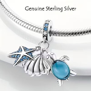 May include: Genuine Sterling Silver charm featuring a starfish, seashell, and sea turtle pendant. The starfish and turtle have blue accents. The charm is attached to a silver snake chain.