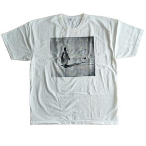 May include: White t-shirt with a crew neck and short sleeves. The shirt features a black and white image of a penguin on a textured background. The penguin is standing on a line, casting a shadow.