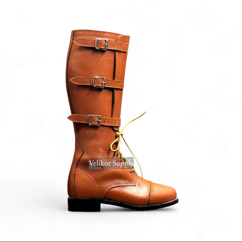 May include: A tall, brown leather boot with three buckle straps and a lace-up front. The boot has a rounded toe and a small, black heel. The boot is designed for riding or equestrian activities.