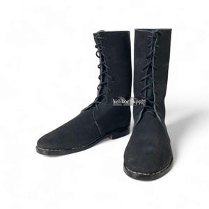 May include: A pair of black mid-calf boots featuring a lace-up front closure with black laces, rounded toes, and visible stitching along the sole edges. The text Velikor Supply is printed in white on the side of the right boot shaft.