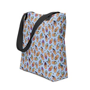 May include: A light blue tote bag featuring a repeating pattern of cartoon trolls with colorful hair. The trolls have various hair colors, including rainbow hues. The bag has black straps and is designed for carrying items.