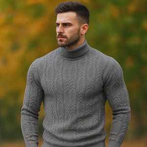 May include: A gray cable-knit turtleneck sweater. The sweater has a high, ribbed collar and a textured pattern. The sleeves are long, and the fit appears to be slim. The background is blurred, with autumn colors.