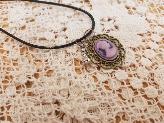 A Touch of Wonderland Purple filigree eged Cameo on black cord with silver rook necklace