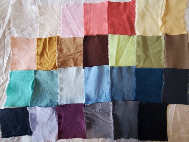 May include: A collection of 25 fabric swatches in various colors, including pink, red, yellow, green, blue, brown, purple, and gray. The swatches are arranged in a grid pattern on a white surface.