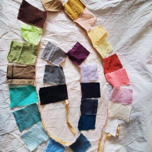 May include: A collection of fabric swatches in various colors, including brown, green, blue, purple, and pink, arranged in a circle on a white surface.