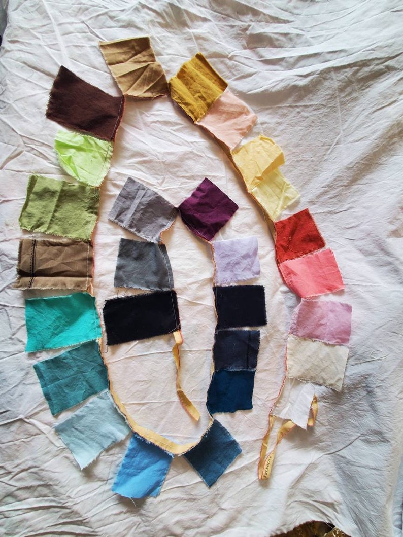 May include: A collection of fabric swatches in various colors, including brown, green, blue, purple, and pink, arranged in a circle on a white surface.