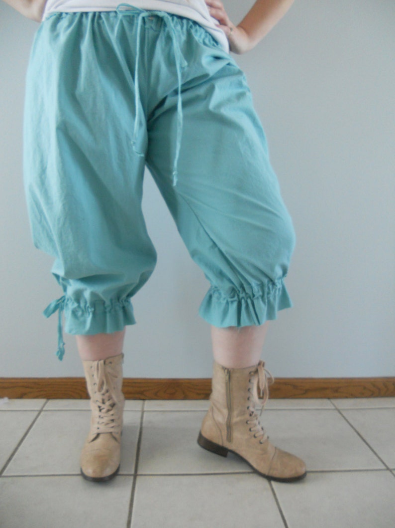 May include: A pair of light blue cotton bloomers with a ruffled hem and a drawstring waist. The bloomers are worn with tan lace-up boots.