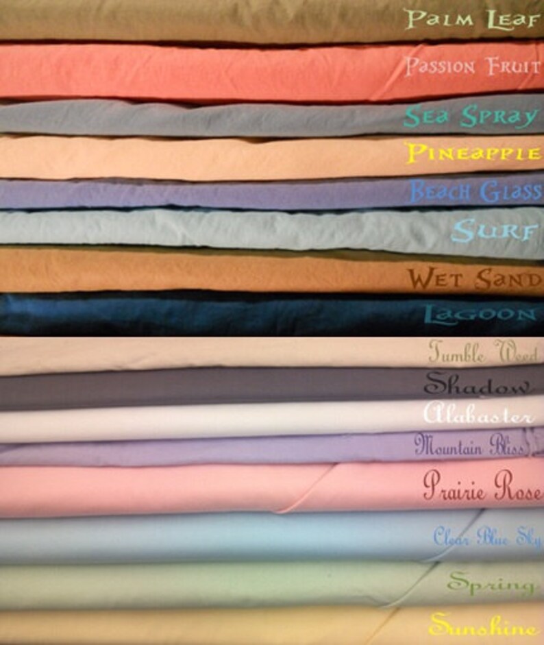 May include: A stack of 18 fabric swatches in various colors, including shades of blue, green, pink, and brown. The swatches are labeled with names like "Palm Leaf", "Passion Fruit", "Sea Spray", "Pineapple", "Beach Glass", "Surf", "Wet Sand", "Lagoon", "Tumble Weed", "Shadow", "Alabaster", "Mountain Bliss", "Prairie Rose", "Clear Blue Sky", "Spring", and "Sunshine".